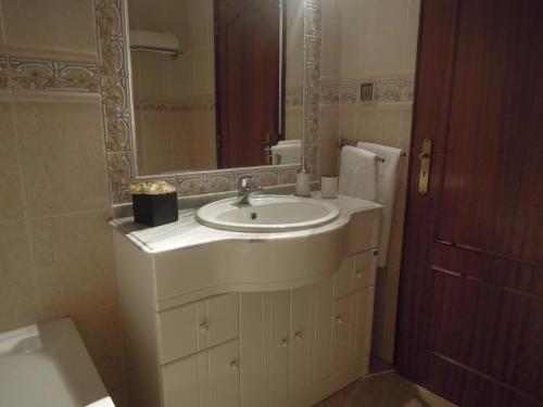 a bathroom with a white sink and a mirror at Home By The Sea in Sesimbra