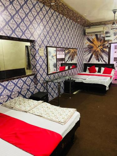 a room with two beds and a wall with a mirror at Appna Ghar Hotel in Amritsar