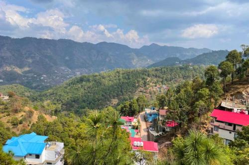 a group of houses on a hill with mountains in the background at Kasauli Hill crest By Xaria Luxury Studio Apartment in Kasauli