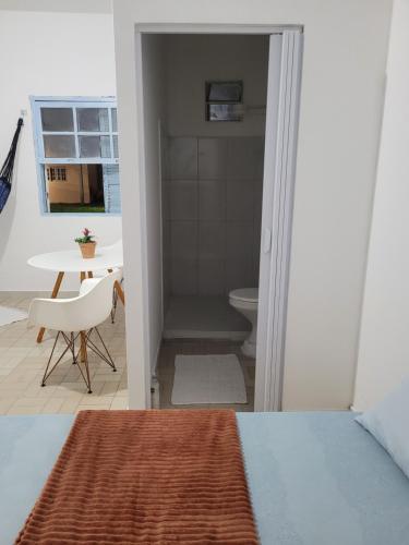 a bedroom with a bathroom with a toilet and a table at Suíte Grão de Areia - de frente para o mar in Bertioga