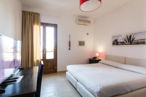 a bedroom with a bed and a desk and a computer at Hotel Cavalluccio Marino in Lampedusa