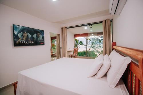 una camera da letto con un letto bianco e una finestra di Pousada Vista pro mar Ilhabela a Ilhabela