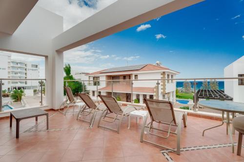 a balcony with chairs and tables and a view of a building at Seafront Protaras Villas in Protaras