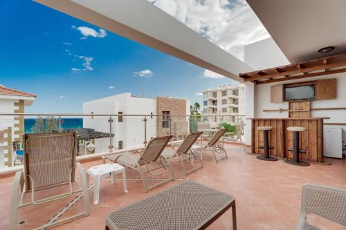 a balcony with chairs and a flat screen tv at Seafront Protaras Villas in Protaras