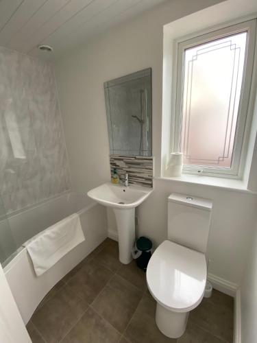 a white bathroom with a toilet and a sink at The Bungalow at Parkside, 4 ensuite bedrooms in Goole
