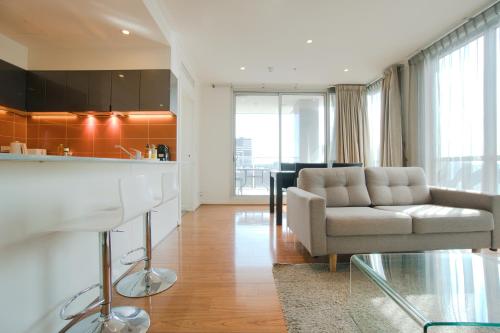 a living room with a couch and a kitchen at Amyra Residences at the Rowlands Apartments in Adelaide