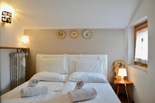 un lit blanc avec deux oreillers et des horloges au mur dans l'établissement Hostdomus - Rifugio delle Stelle, à Sestrières