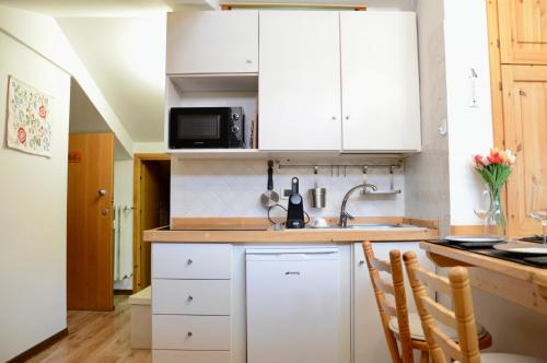 une cuisine avec des armoires blanches et un évier dans l'établissement Hostdomus - Rifugio delle Stelle, à Sestrières