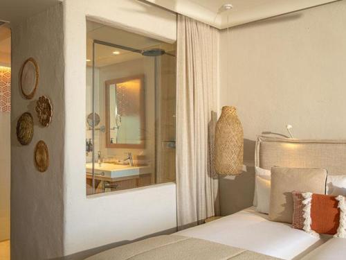 a bedroom with a bed and a bathroom with a mirror at DAIA Slow Beach Hotel Conil - Adults Only Recommended in Conil de la Frontera
