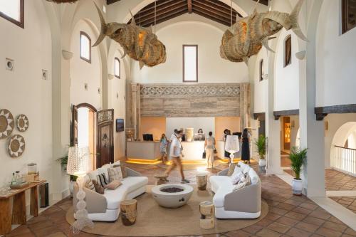 a large room with white furniture and people walking in it at DAIA Slow Beach Hotel Conil - Adults Only Recommended in Conil de la Frontera