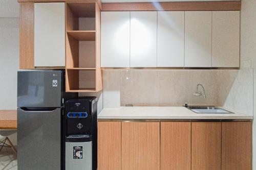a kitchen with white cabinets and a refrigerator at Homey Studio at Patraland Amarta Apartment By Travelio in Beran-kidul