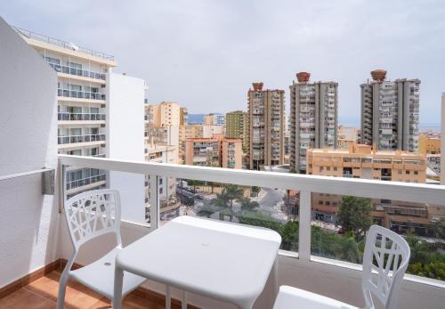 a balcony with a white table and chairs and a city at Sandos Griego in Torremolinos