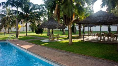 a resort with a swimming pool with tables and umbrellas at Pekan Hotel in Accra