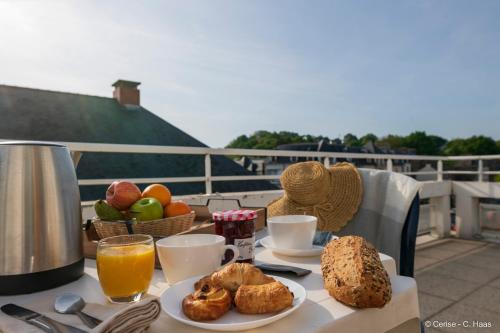 une table avec un petit-déjeuner composé de pain et de jus d'orange dans l'établissement CERISE Lannion, à Lannion