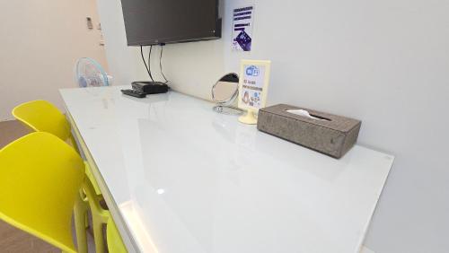 a room with a white desk with a tv and yellow chairs at ChaoPingJia Fengge Guesthouse in Wujie