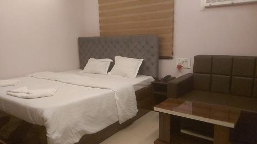a hotel room with a bed and a chair at Hotel Hangout in Jangipur