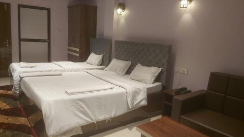 a bedroom with two beds with white sheets at Hotel Hangout in Jangipur