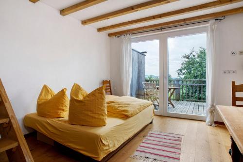 a bedroom with a bed with yellow pillows and a balcony at Kombi Wohnung in Deggenhausertal