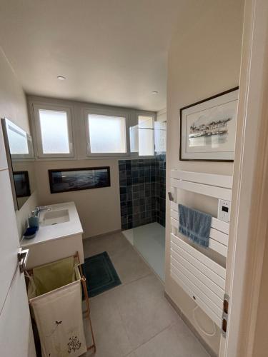 La salle de bains est pourvue d'un lavabo et d'une douche avec fenêtres. dans l'établissement Chambre près de la petite Mer de Gâvres, à Riantec