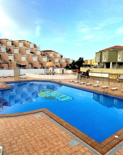 a large swimming pool with chairs in front of a building at MI CASA ORLANDO Fañabe in Adeje