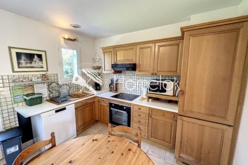 a kitchen with wooden cabinets and a wooden table at Maison de vacances tout confort - À 100m de la mer in Port-Louis