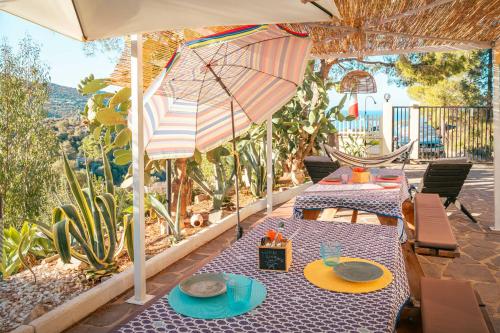 een patio met 2 tafels en een parasol bij Villa Bella Salmagi - Surya Sardinia Holidays & Yoga in Capitana