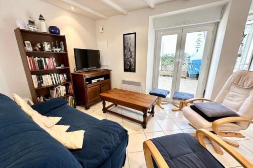 a living room with a blue couch and a tv at Maison de charme Terrasse 5min des plages in Port-Louis
