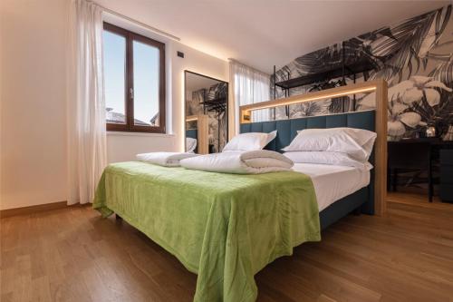 a bedroom with a large bed with a green blanket at Hotel Lago Di Garda in Malcesine