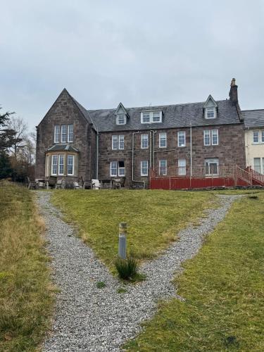 a large brick building with a gravel road in front of it at Loch Maree Hotel in Talladale