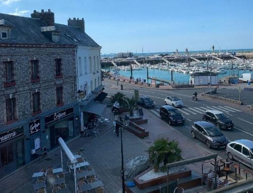a street with cars parked in a parking lot next to a harbor at Appartement à Fécamp avec vue port et mer Le Sémaphore in Fécamp