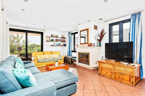 a living room with blue couches and a flat screen tv at Villa Thalassa by Villa Plus in Son Xoriguer