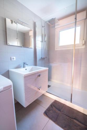 une salle de bain avec un lavabo blanc et une douche dans l'établissement Duplex dans chalet avec superbe vue lac et piscine commune, à Gérardmer
