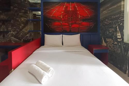 uma cama em um quarto com uma pintura de teia de aranha na parede em Good Deal Studio Apartment at Student Castle Yogyakarta By Travelio em Seturan