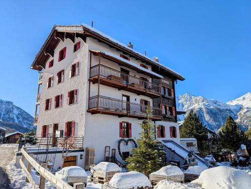 a building in the mountains with snow on the ground at Zur Alten Post - Old Post Office in Grächen
