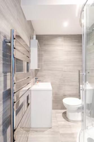 a bathroom with a white toilet and a sink at Modern House with relaxing Hot tub in Uxbridge