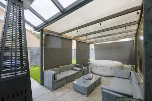 a screened in patio with a couch and a table at Modern House with relaxing Hot tub in Uxbridge
