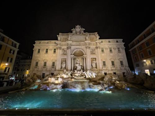 a building with a fountain in front of it at night at Fil Rouge in Ciampino
