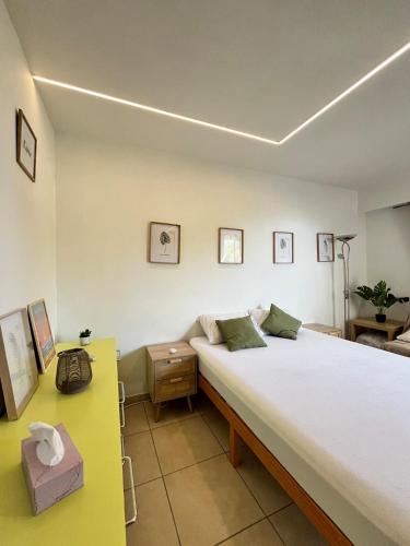 - une chambre avec un grand lit et une table jaune dans l'établissement Terrasse, piscine, clim, proche aéroport et plage, à Saint-Laurent-du-Var