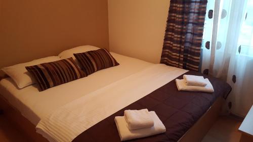 a bed with two folded towels on top of it at Hotel Amicus in Mostar