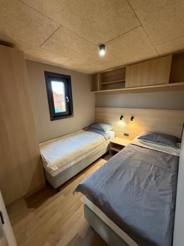 a bedroom with two beds and a window at Mobile Home Aura, Village Twins in Pakoštane
