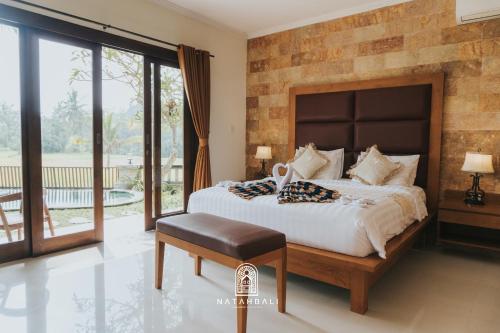 a bedroom with a large bed and a balcony at The paddies villa #2 in Tampaksiring