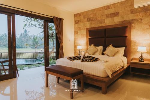 a bedroom with a large bed and a balcony at The paddies villa #2 in Tampaksiring