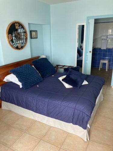 a large bed with blue pillows in a bedroom at La Grande Mare in Saint-Benoît-des-Ondes