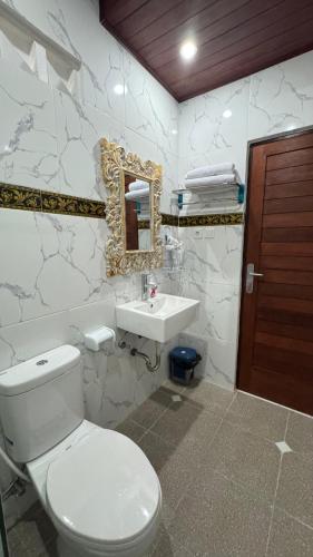 a bathroom with a toilet and a sink and a mirror at Langit Guest House Canggu in Canggu