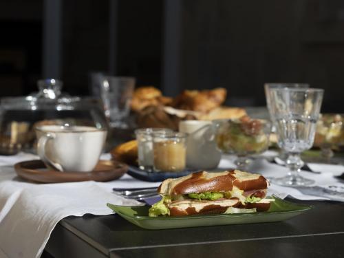 リブルヌにあるLa Maison Mulatoの緑の皿の上にサンドイッチが置かれたテーブル