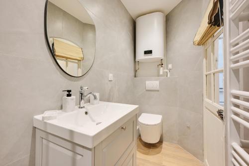 une salle de bain avec un lavabo blanc et un miroir dans l'établissement Appartement Triplex à Saint-Germain-des-Prés, à Paris