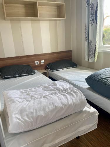 deux lits dans une chambre avec une fenêtre dans l'établissement Mobilhome close to the pool - Cc110 Siblu Les Charmettes, aux Mathes