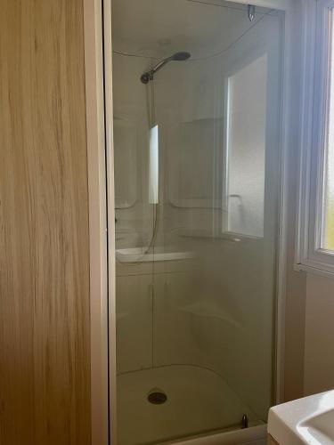 une douche avec une porte vitrée dans une salle de bain dans l'établissement Mobilhome close to the pool - Cc110 Siblu Les Charmettes, aux Mathes