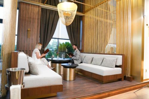 two people sitting in a living room reading at Divan Erbil Hotel in Erbil