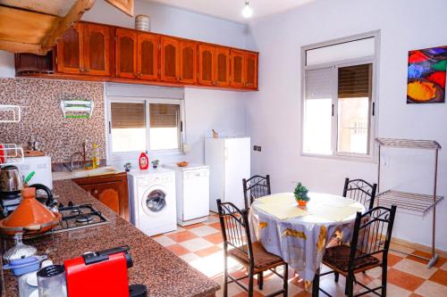 a kitchen with a table and a white refrigerator at Spacious Apartment with Motorcycle Garage, Free Parking, and Air Conditioning in Er Rachidia